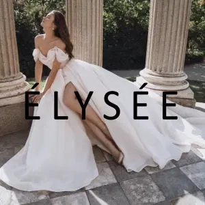 Eine Braut im pompösen Brautkleid sitzt auf einer Mauer umgeben von Säulen